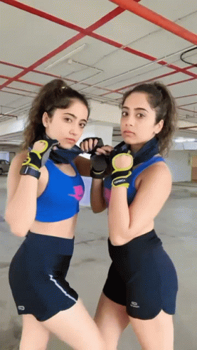Two Women Standing Next To Each Other With One Wearing A Blue Crop Top GIF
