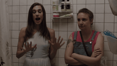 Two Women Talking In Bathroom With I Love You Tattoo GIF