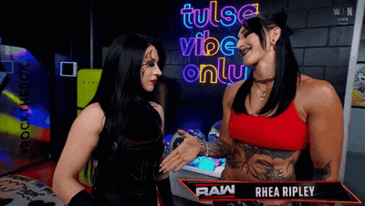 Two Women Talking In Front Of A Sign That Says Tulsa Vibe Only GIF