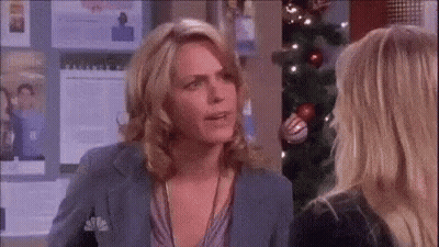 Two Women Talking In Front Of Christmas Tree GIF
