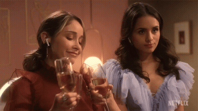 Two Women Toasting With Champagne Glasses With A Netflix Logo In The Corner GIF