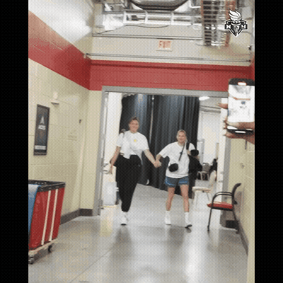 Two Women Walking Down Hallway With Exit Sign