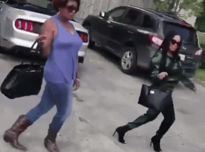 Two Women Walking Down Street Past Parked Car GIF