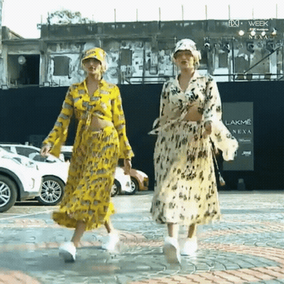 Two Women Walking in Front of Lakme Sign