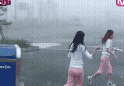 Two Women Walking Past Sign Saying M GIF