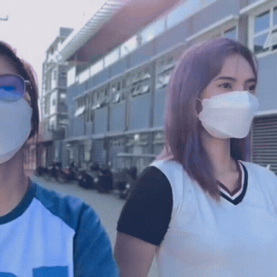 Two Women Wearing Face Masks Standing Next To Each Other In Front Of A Building GIF