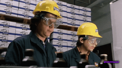 Two Women Wearing Hard Hats And Safety Goggles Are Working In A Factory GIF