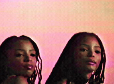 Two Women With Dreadlocks In Front Of Pink Wall GIF