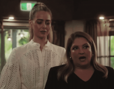 Two Women With Green Exit Sign Above GIF