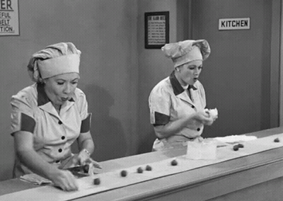 Two Women Working in Kitchen With Sign