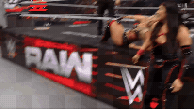 Two Women Wrestling In Front Of A Raw Banner GIF