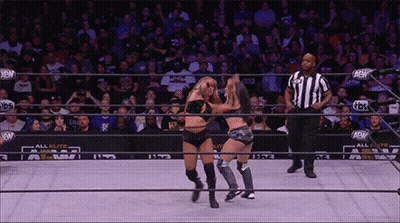 Two Women Wrestling In Ring With Referee And Crowd GIF