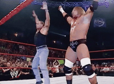 Two Wrestlers Are Dancing In A Wrestling Ring While A Crowd Watches . GIF
