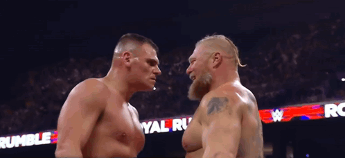Two Wrestlers Are Facing Each Other In Front Of A Crowd And A Sign That Says Rumble GIF