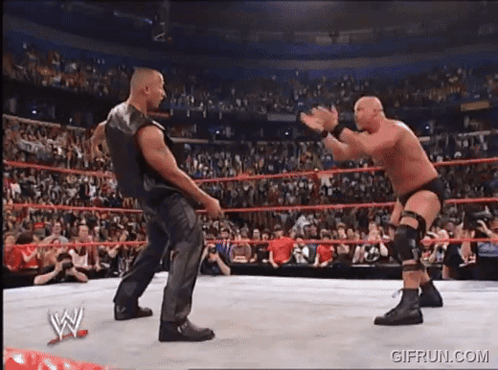 Two Wrestlers Are Fighting In A Wrestling Ring With A Crowd Watching .. GIF