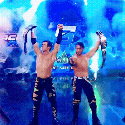 Two Wrestlers Are Holding Up Their Championship Belts In Front Of A Sign That Says Next Saturday GIF