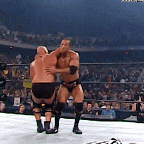 Two Wrestlers Are Hugging Each Other In A Wrestling Ring In Front Of A Crowd . GIF