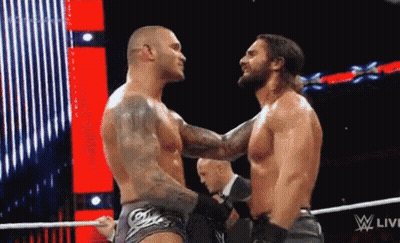 Two Wrestlers Are Hugging Each Other In A Wrestling Ring While A Referee Watches . GIF