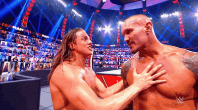 Two Wrestlers Are Hugging Each Other In A Wrestling Ring With A Crowd In The Background . GIF