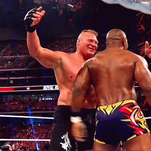 Two Wrestlers Are Hugging In Front Of A Crowd With A Sign That Says Royal Rumble In The Background GIF