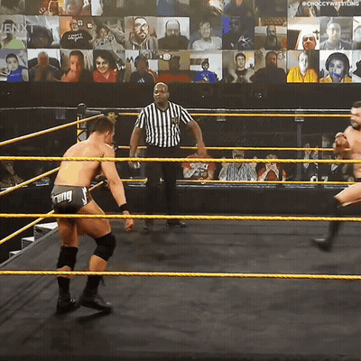 Two Wrestlers Are In A Wrestling Ring With A Referee In Front Of A Crowd GIF