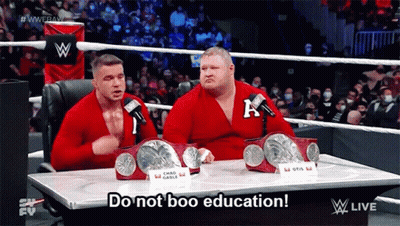Two Wrestlers Are Sitting At A Table With The Words Do Not Boo Education GIF