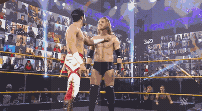 Two Wrestlers Are Standing In A Wrestling Ring With A Crowd Behind Them And The Letters W On The Wall GIF