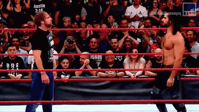 Two Wrestlers Are Standing In A Wrestling Ring With A Crowd Watching And A Banner That Says Austin 3:16 GIF
