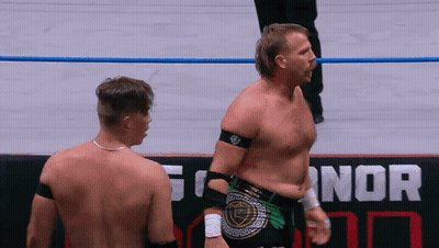 Two Wrestlers Are Standing In Front Of A Sign That Says Nor On It GIF