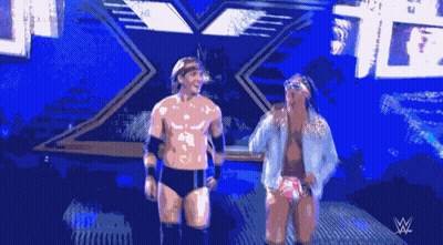 Two Wrestlers Are Standing In Front Of A Sign That Says W GIF