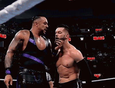 Two Wrestlers Are Standing Next To Each Other In A Ring . GIF