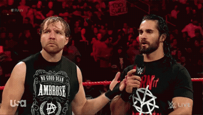 Two Wrestlers Are Standing Next To Each Other In A Wrestling Ring And One Of Them Is Wearing A Shirt That Says Ambrose GIF