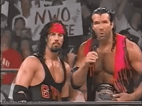 Two Wrestlers Are Standing Next To Each Other In Front Of A Crowd While Holding Microphones . GIF