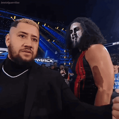 Two Wrestlers Are Standing Next To Each Other In Front Of A Sign That Says " Mack " GIF