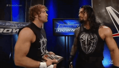Two Wrestlers Are Standing Next To Each Other In Front Of A Tv Screen . GIF