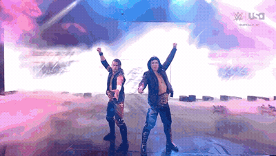 Two Wrestlers Are Standing On A Stage With Their Arms In The Air In Front Of A Screen That Says W Usa GIF