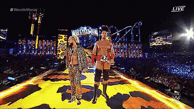 Two Wrestlers Are Walking On A Stage With A Sign That Says Wrestlemania GIF