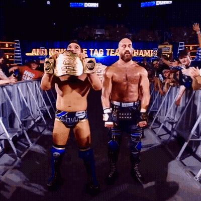 Two Wrestlers By Sign Saying Tag Team Champ GIF
