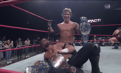 Two Wrestlers In A Ring With A Sign That Says Impact In The Background GIF