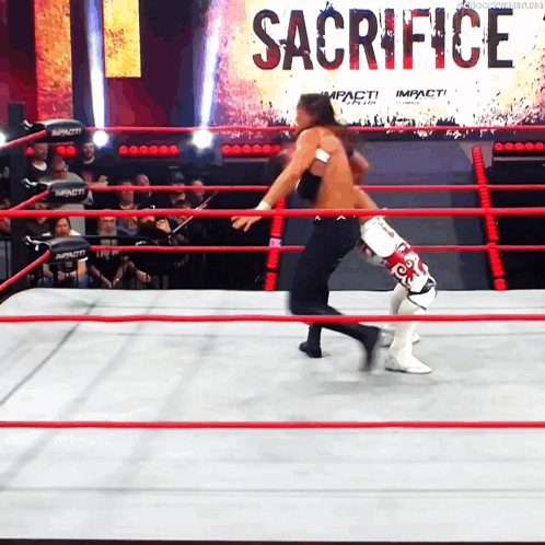 Two Wrestlers In A Ring With A Sign That Says Sacrifice On It GIF