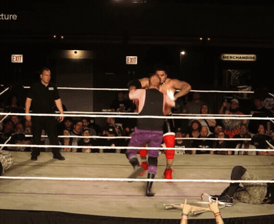 Two Wrestlers In A Ring With An Exit Sign Behind Them GIF