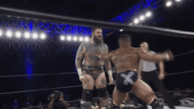 Two Wrestlers In A Ring With One Wearing A Pair Of Shorts With The Letter X On Them GIF