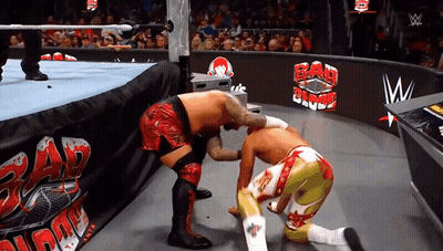 Two Wrestlers In A Wrestling Ring With A Sign That Says Bad Blood GIF