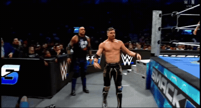 Two Wrestlers In A Wrestling Ring With A Smack Sign In The Background GIF