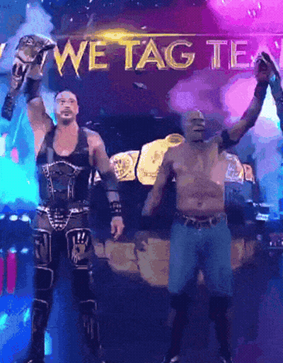Two Wrestlers Standing In Front Of A Sign That Says " We Tag Team " GIF