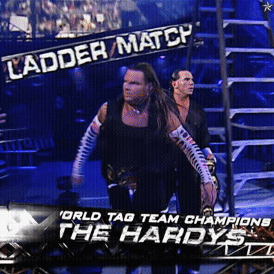 Two Wrestlers Standing In Front Of Ladder Match Banner GIF