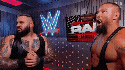 Two Wrestlers Standing In Front Of WWE Sign GIF