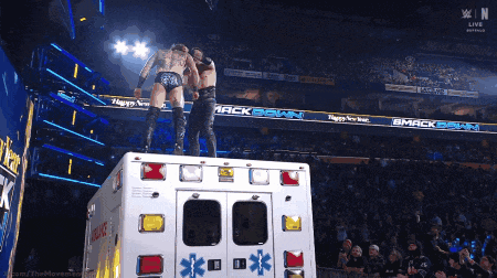 Two Wrestlers Standing On Ambulance Saying Smackdown GIF