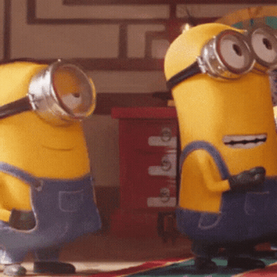 Two Yellow Minions Wearing Blue Overalls And Goggles GIF