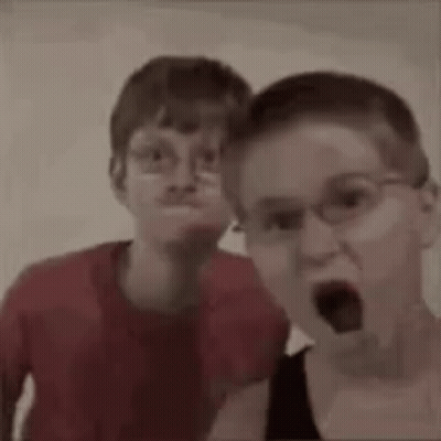 Two Young Boys Wearing Glasses Are Making Funny Faces . GIF